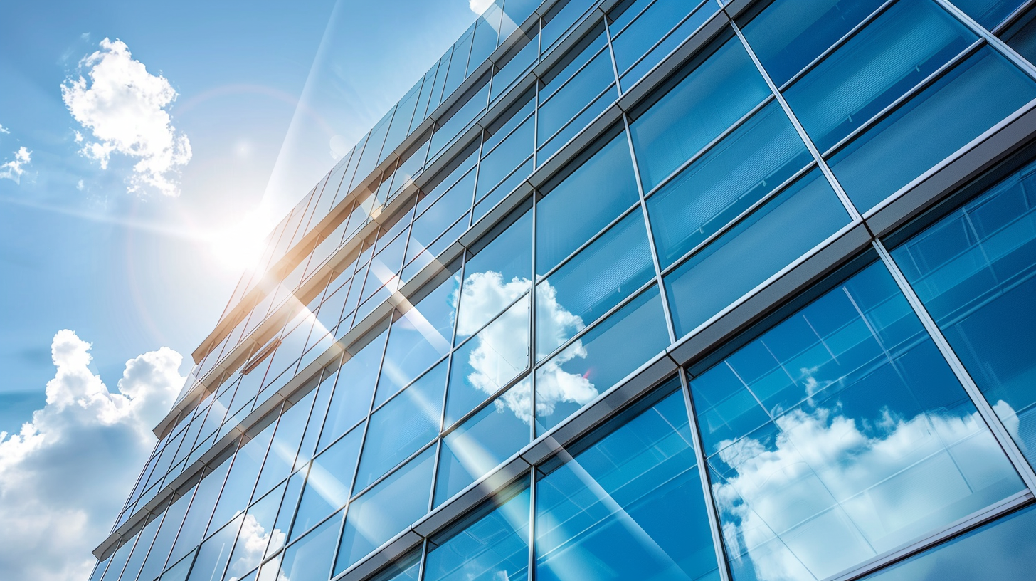 Moderne Glasfassade eines Bürogebäudes unter blauem Himmel.