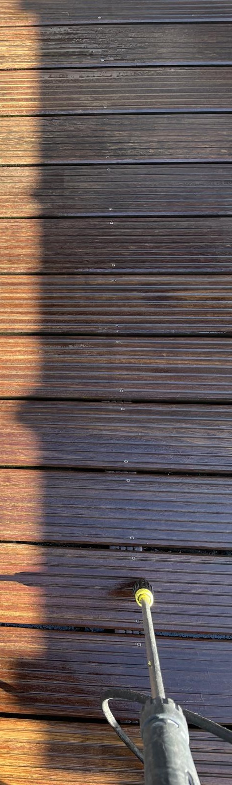 Ein Holzdeck wird mit einem Hochdruckreiniger gereinigt.
