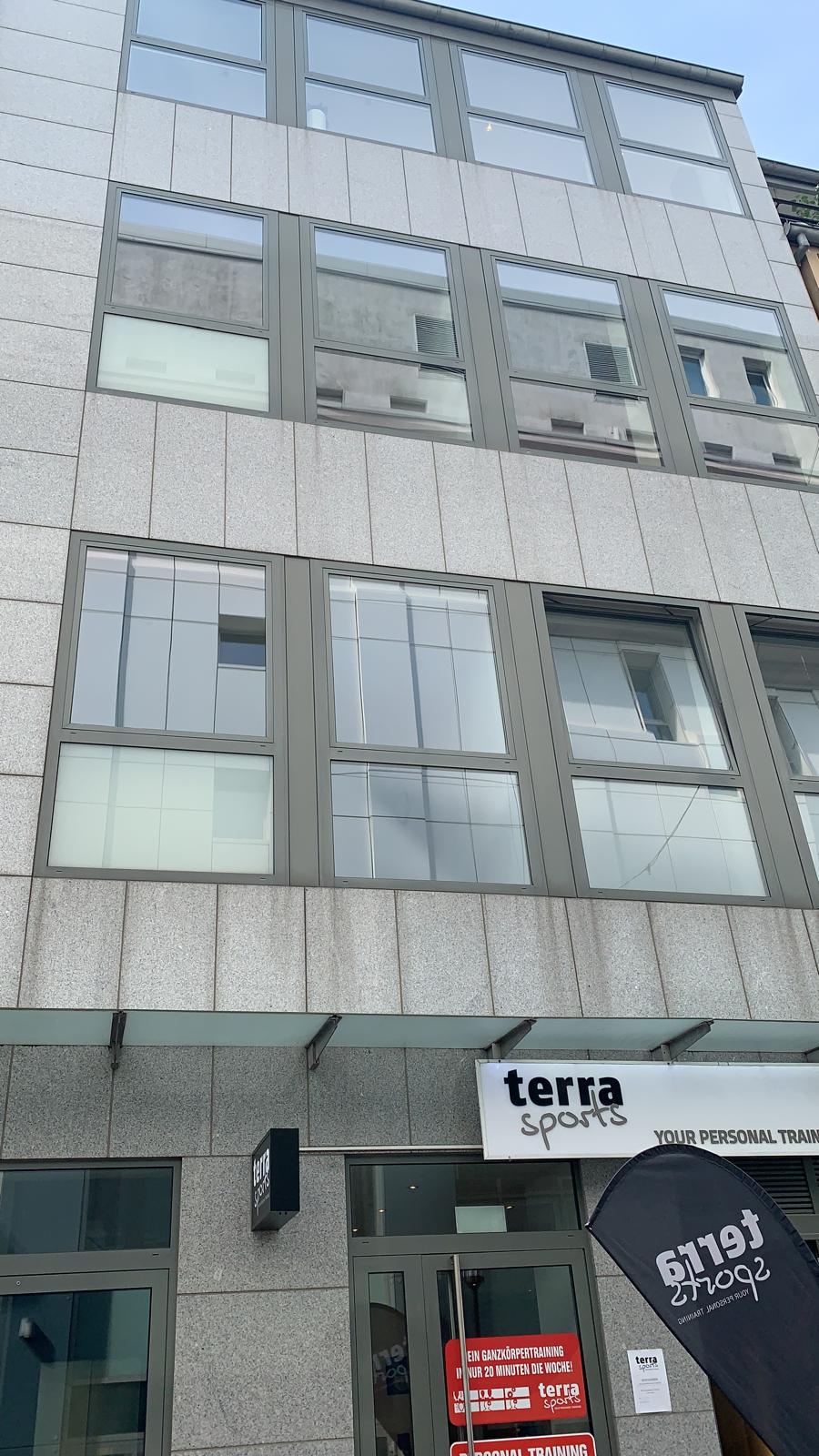 Moderne Fassade eines Fitnessstudios mit großen Fenstern und einem Schild.