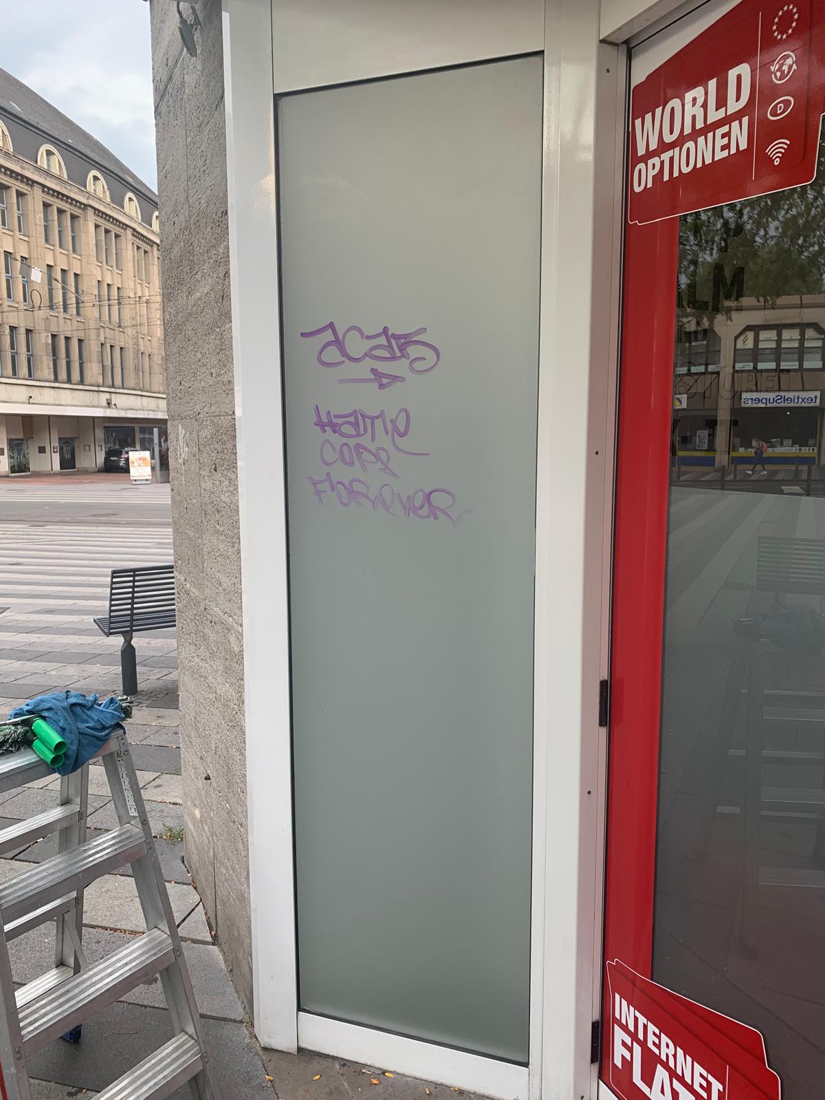 Graffiti auf einer Glasfläche in städtischer Umgebung.