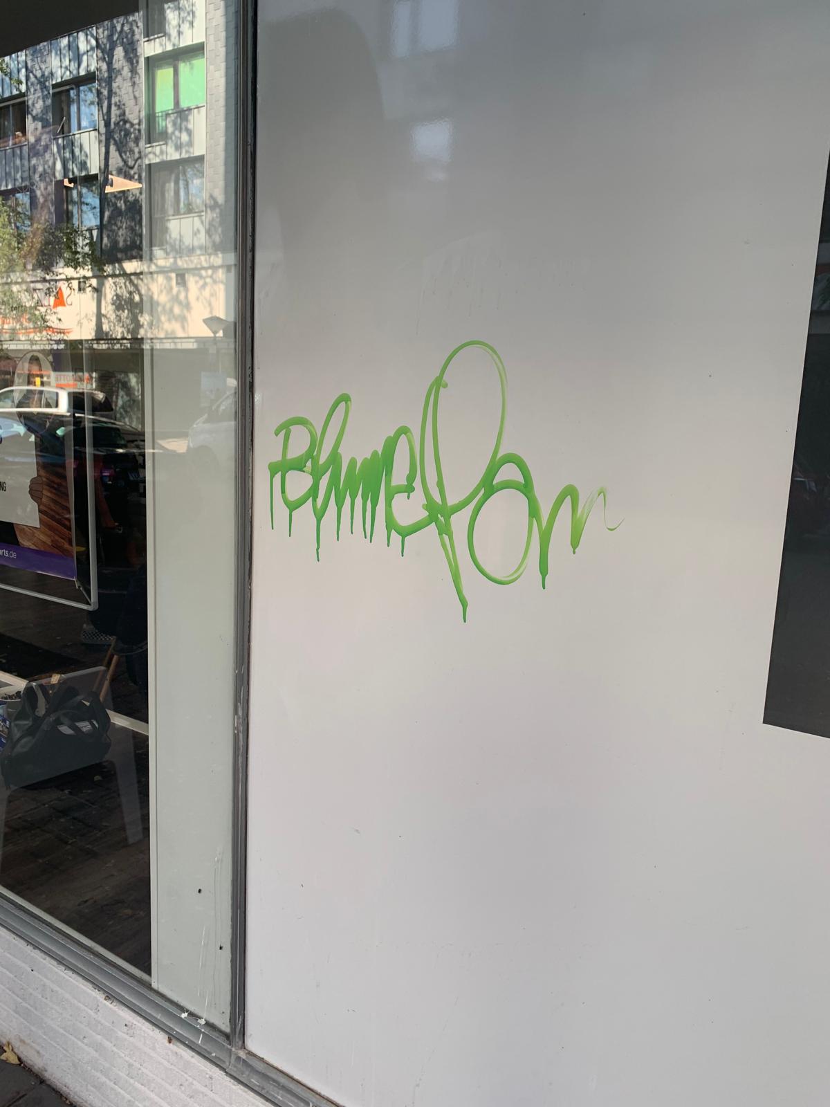 Grünes Graffiti auf einer weißen Wand, urbaner Kontext.