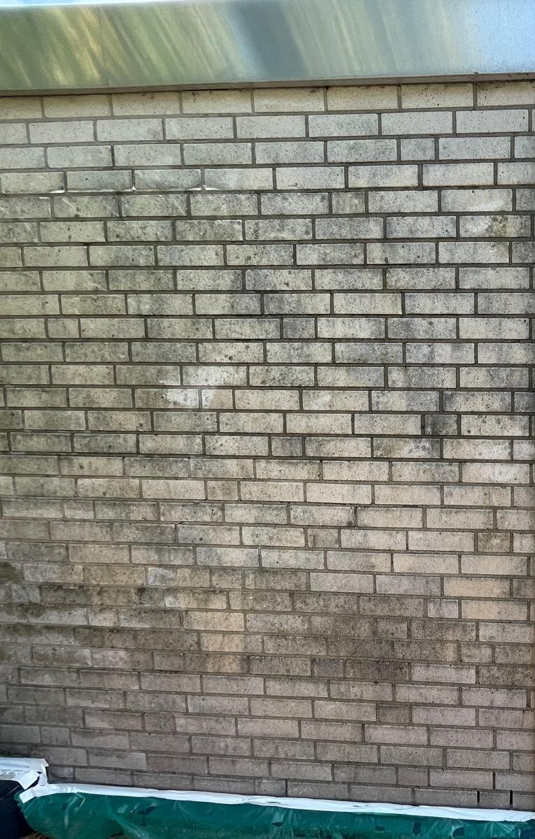 Eine graue Ziegelwand mit Flecken und Verunreinigungen.