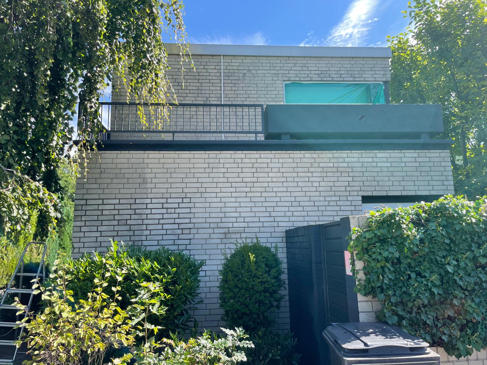 Moderne Architektur mit Balkon und Pflanzen im Vordergrund.