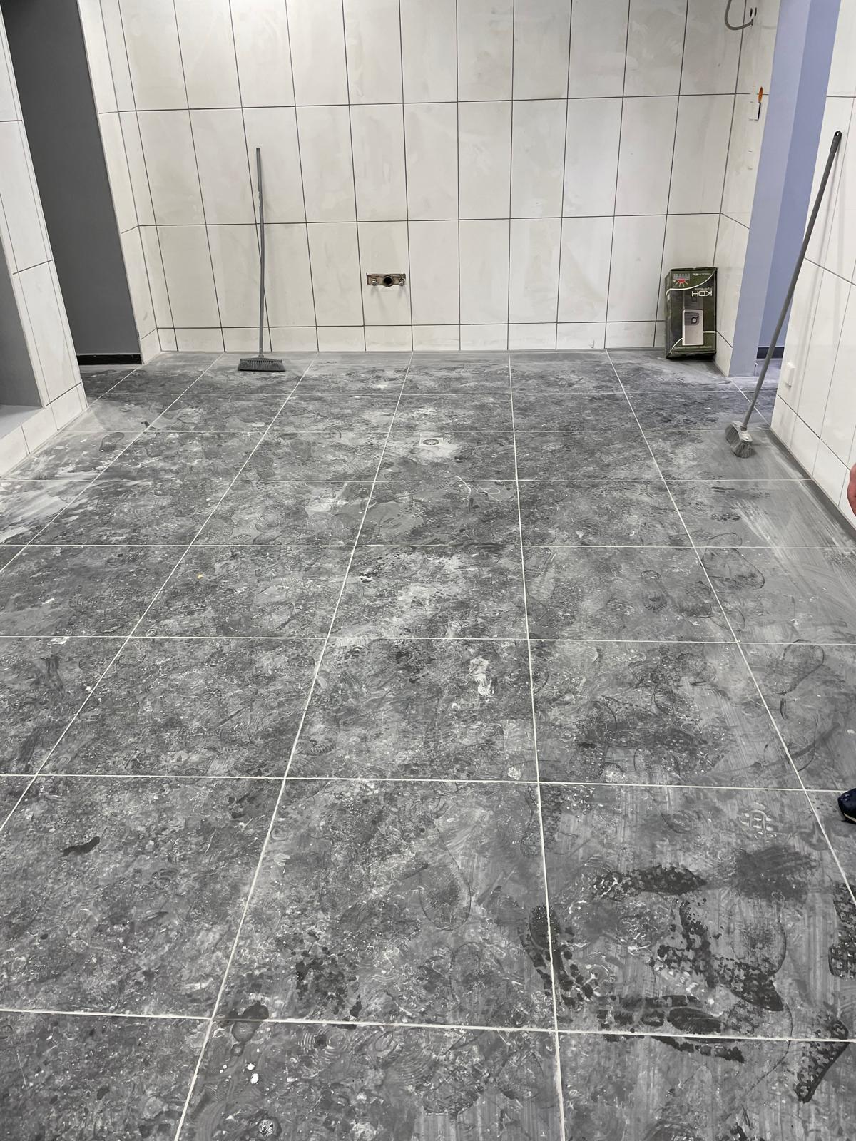 Ein grauer Fliesenboden in einem Raum mit weißen Wänden.