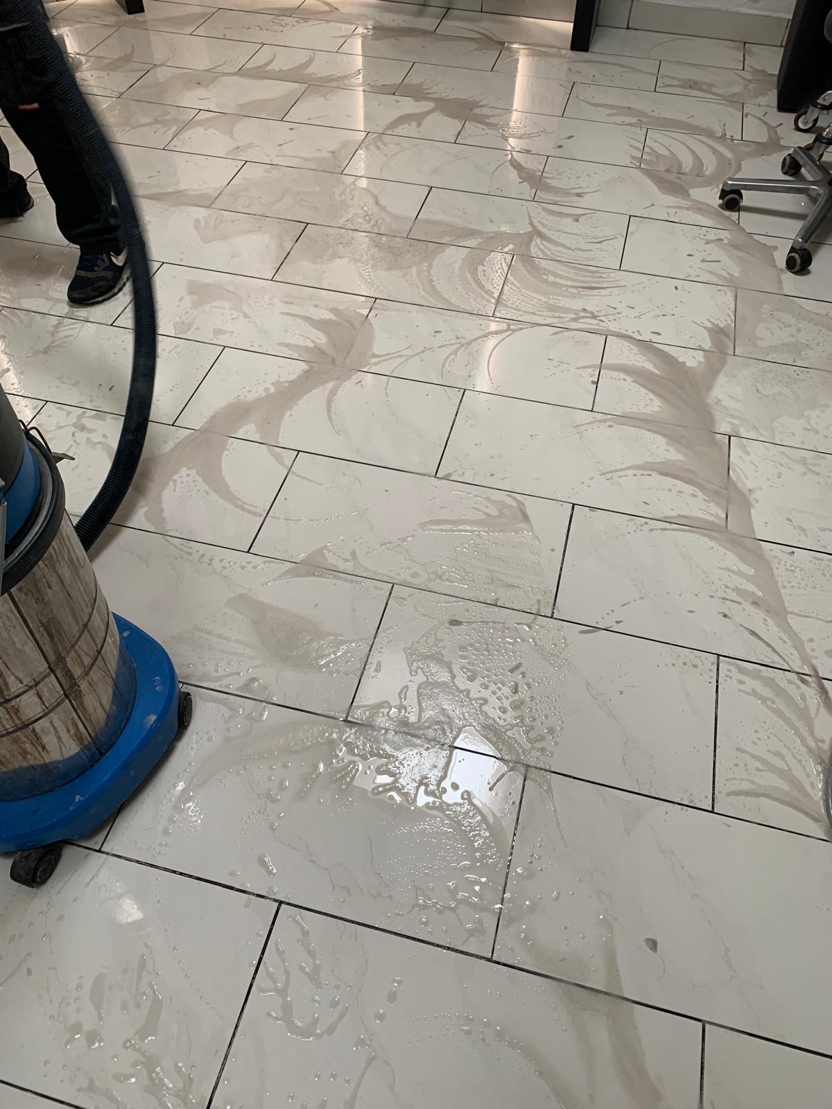 Nasser Boden mit Reinigungsgerät und Wasserflecken.